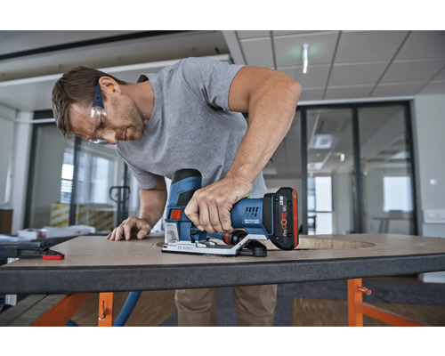 Un homme travaille avec une scie sauteuse sans fil sur une plaque de bois