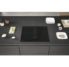 Plaque à induction noire Haier avec hotte aspirante sur un plan de travail de cuisine.