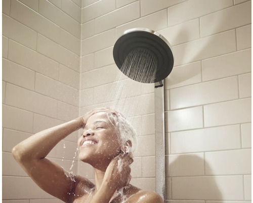 Frau unter einer Regendusche mit rundem Duschkopf