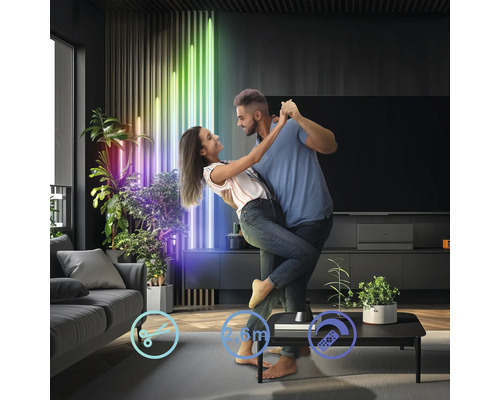 Ein Paar tanzt in einem Wohnzimmer, das mit LED-Lichtern und Zimmerpflanzen dekoriert ist.