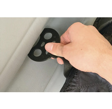 Main fixant une protection de siège auto avec un disque de fixation sur un siège auto