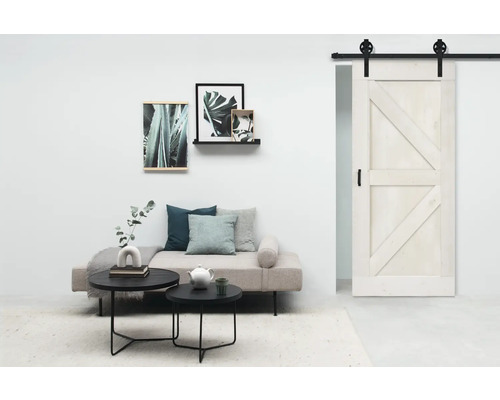 Espace de vie avec porte coulissante, canapé, tables basses et décorations murales pour une ambiance moderne.
