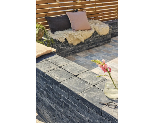 Aménagement de terrasse avec mur en pierre, coussins et décoration