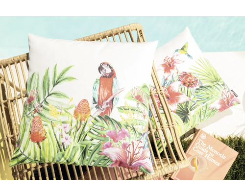 Dekokissen mit Papagei- und Blumenmuster auf Korbstuhl