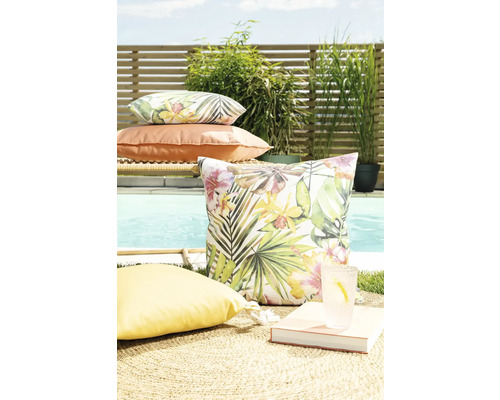 Szene mit Gartenkissen mit floralen Mustern und einfarbigen Kissen auf einem Teppich in der Nähe eines Pools