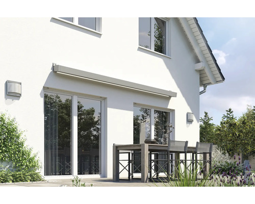 Façade de maison avec store au-dessus de la porte de terrasse et table de jardin avec chaises