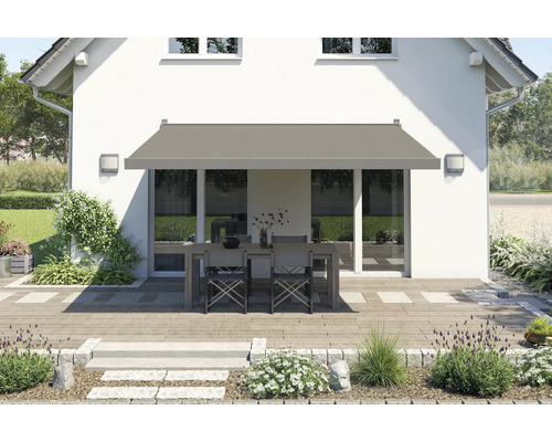 Hausfassade mit ausgefahrener Gelenkarmmarkise über einer Terrasse mit Gartentisch und Stühlen