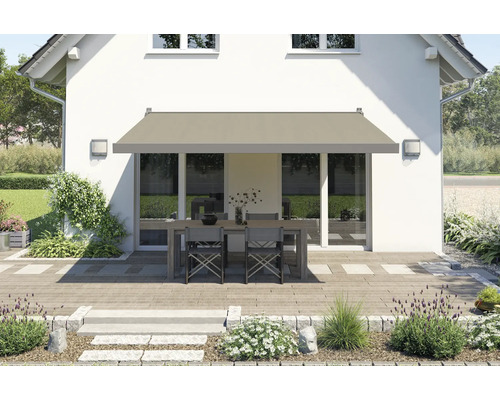 Terrasse mit Markise, Tisch und Stühlen vor einem Haus.