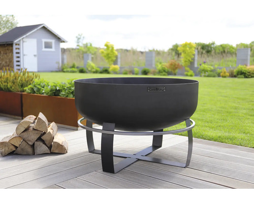 Brasero en acier sur une terrasse de jardin en bois avec une pile de bois