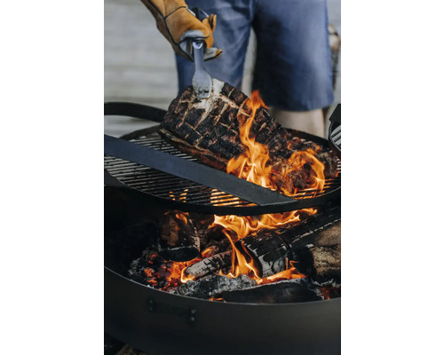 Des aliments sont retournés à la pince sur un barbecue au charbon de bois