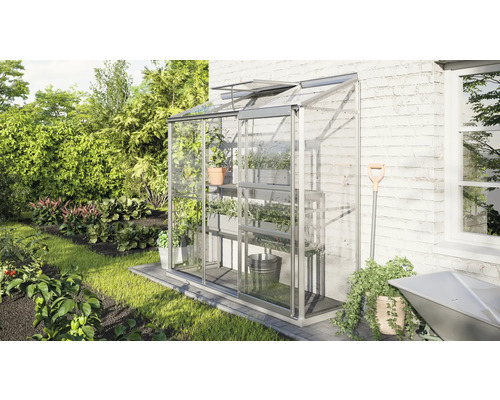 Serre avec étagères à plantes dans le jardin.
