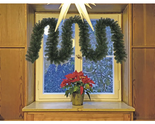 Rebord de fenêtre décoré avec une guirlande de sapin et une étoile de Noël