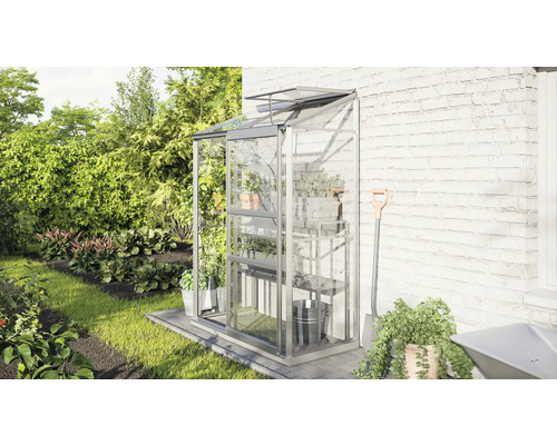 Serre murale en verre avec étagères contre un mur de maison dans le jardin