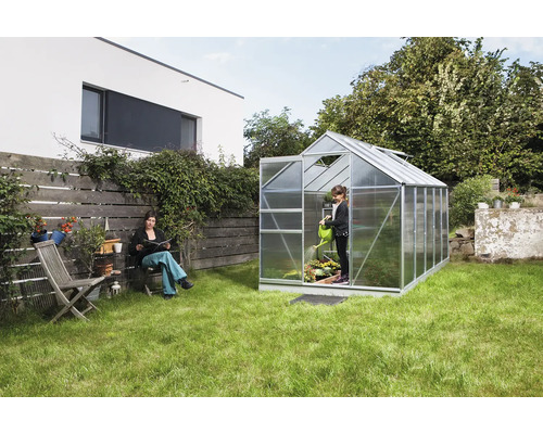 Scène de jardin avec serre, femme et enfant jardinent