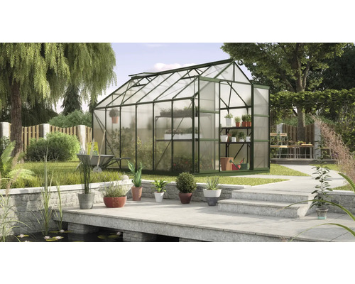 Gewächshaus mit Pflanzenregalen in einem Garten mit Teich und Steintreppe