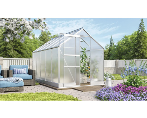 Serre avec porte ouverte dans un jardin avec mobilier de jardin et parterres de fleurs.