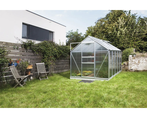 Serre dans jardin avec pelouse et mobilier de jardin