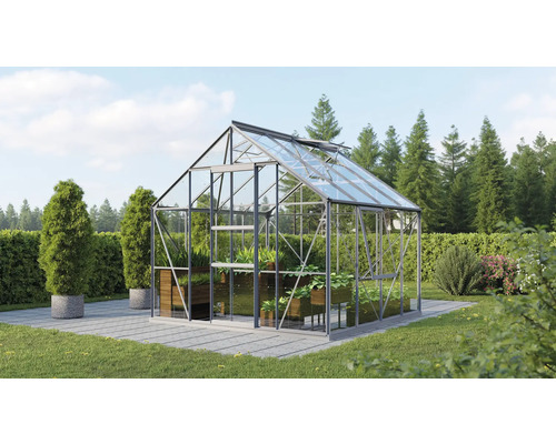 Serre en verre avec des plantes dans un jardin.