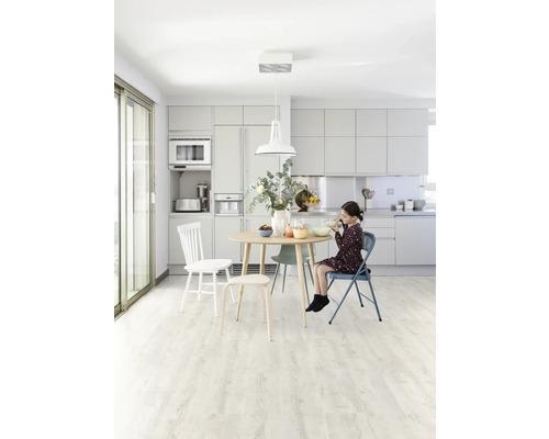 Heller Küchenraum mit Esstisch, Stühlen und einem Mädchen beim Essen.