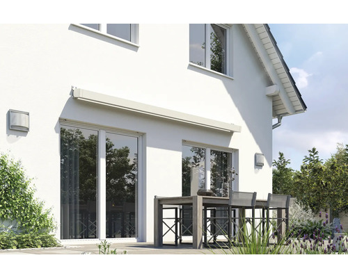 Hausfassade mit Markise über Terrassentür und Sitzgruppe