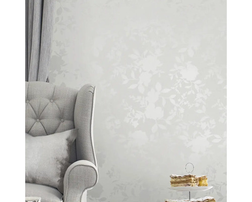 Szene mit Stuhl, Vorhang, Kuchen und floral gemusterter Tapete für ein helles, organisiertes Ambiente