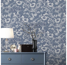 Dekoratives Zimmer mit blumiger Vliestapete auf der Wand, Kommode, Lampe und Dekorationen.