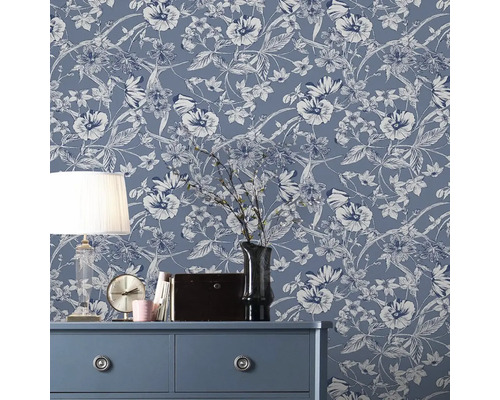 Dekoratives Zimmer mit blumiger Vliestapete auf der Wand, Kommode, Lampe und Dekorationen.