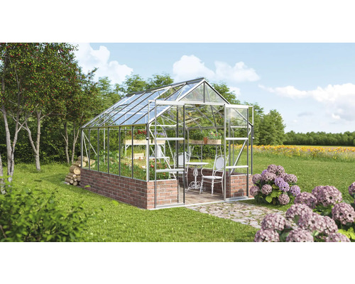 Gewächshaus aus Glas und Stein im Garten mit Tisch und Stühlen