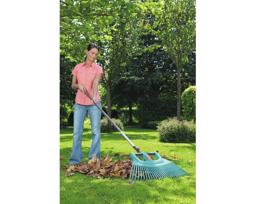 Femme ratissant des feuilles avec un râteau à feuilles dans le jardin.