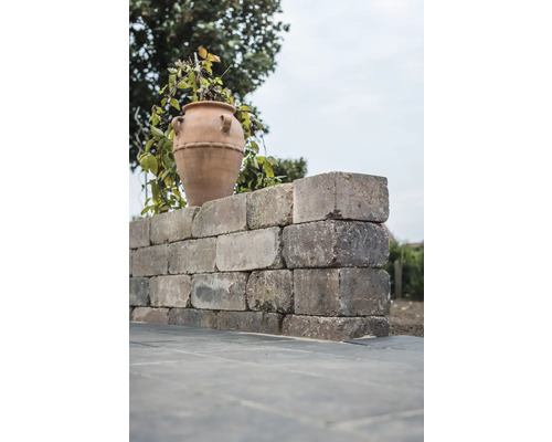 Un mur en pierres avec un vase dans le jardin.