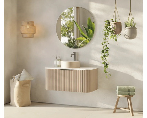 Salle de bain lumineuse avec meuble-lavabo, miroir, plantes suspendues, lampe et panier à linge pour une ambiance conviviale