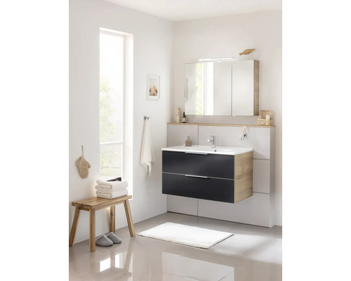 Salle de bains lumineuse avec lavabo, armoire de toilette, tabouret, serviettes et tapis de bain.