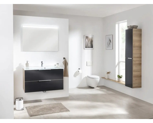 Salle de bain lumineuse avec meuble-lavabo, miroir, WC et armoire haute pour une ambiance moderne.