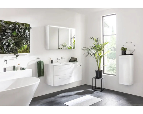 Salle de bains avec baignoire îlot, meuble-lavabo avec miroir, armoire suspendue et décoration végétale pour une ambiance claire et moderne.