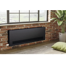 Un radiateur noir est monté sur un mur en briques sous une fenêtre.