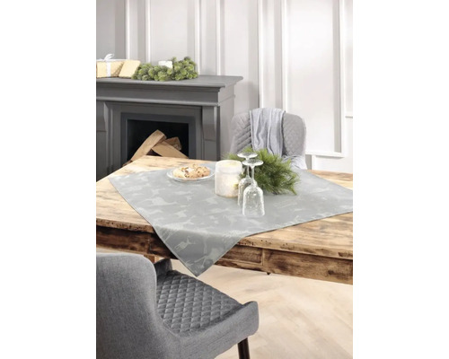 Table de salle à manger décorative avec chemin de table, table mise et cheminée en arrière-plan.