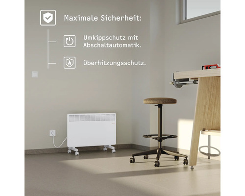 Weißer Konvektor-Heizkörper mit Rollen und Sicherheitsfunktionen in einem Zimmer.