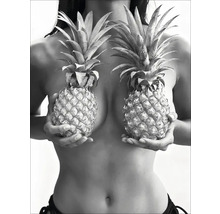 Une femme tient deux ananas devant sa poitrine.