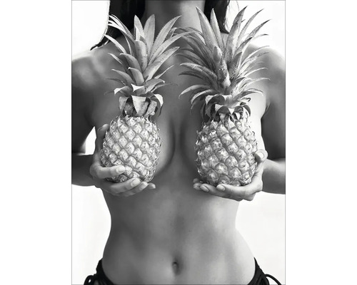 Une femme tient deux ananas devant sa poitrine.