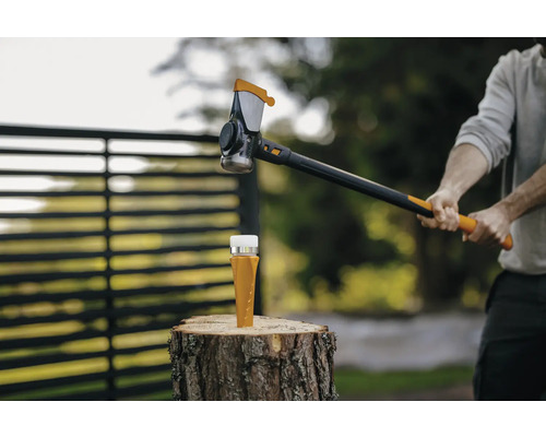 Holzspalter auf Holzscheit und Person mit Spalthammer