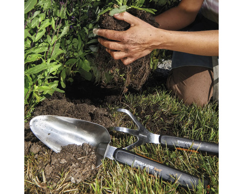 Scène de jardinage avec plantoir, cultivateur et personne plantant une plante