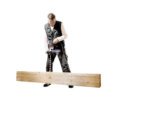 Un homme perce une planche de bois avec une perceuse.