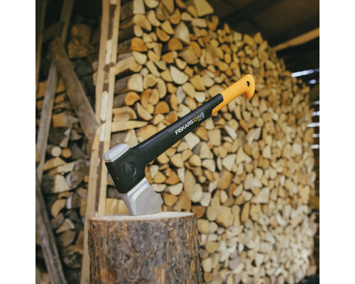 Fiskars Spaltaxt auf einem Hackklotz vor einem Stapel Holz