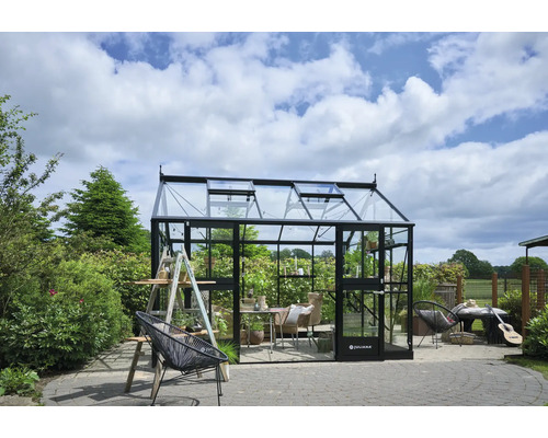 Gewächshaus im Garten mit Pflanzen, Möbeln und Gartengeräten.