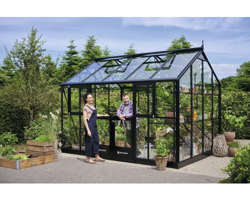 Gewächshaus aus Glas und Metall mit zwei Personen im Garten.
