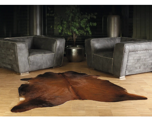 Wohnzimmer mit zwei grauen Ledersesseln und einem braunen Kuhfellteppich
