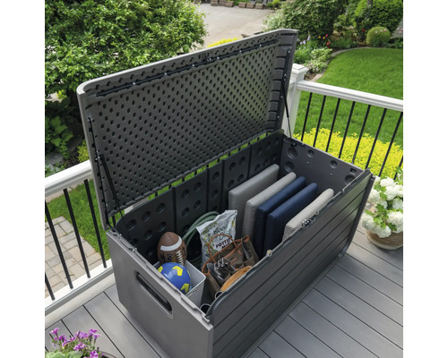 Geöffnete graue Gartenbox auf einer Terrasse mit Gartenwerkzeug und Kissen