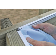 Une personne installe un film de confidentialité sur une clôture en bois.