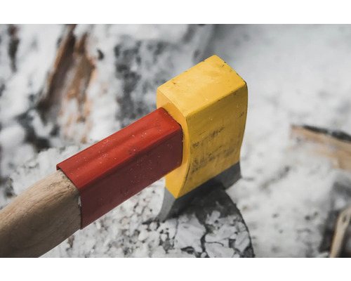 Axt mit gelbem Kopf und rotem Griffschutz auf einem Baumstumpf.