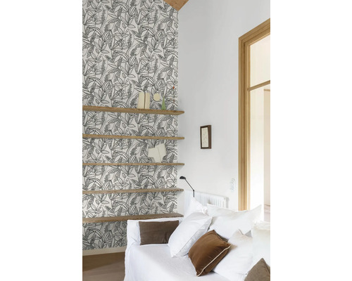 Salon avec papier peint à motifs, étagères en bois et canapé blanc.